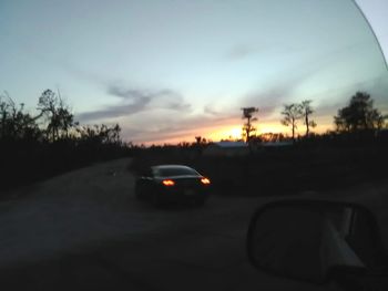 Cars on road against sky during sunset