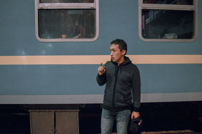 Thoughtful young man standing against train