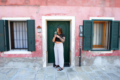 Woman standing by window of house