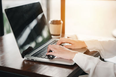 Midsection of woman using laptop on table