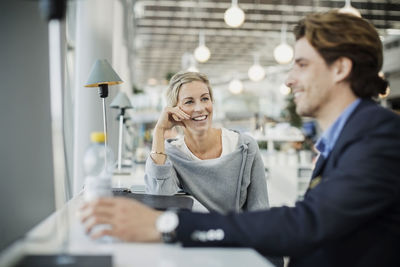 Happy businesswoman talking to male colleague at airport cafe