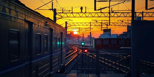 Train on railroad tracks against sky during sunset