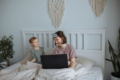 Mother and daughter looking at laptop sitting on bed