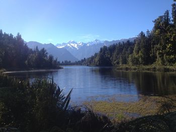 Scenic view of lake and mountains against blue sky