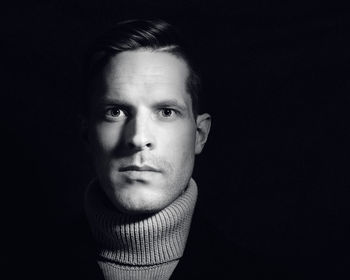 Close-up portrait of young man against black background