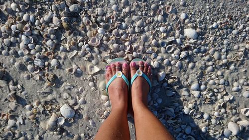 Low section of woman standing on pebbles