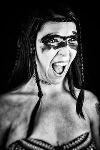 Close-up of woman with make-up shouting against black background