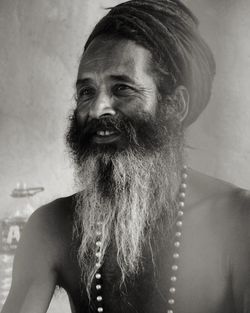 Shirtless man looking away while sitting against wall