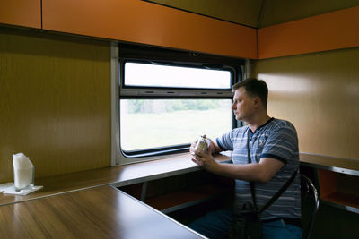 Man holding drink while sitting in cafe