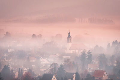 Aerial view of city buildings against sky and fog