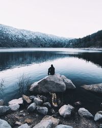 Man relaxing by lake against sky