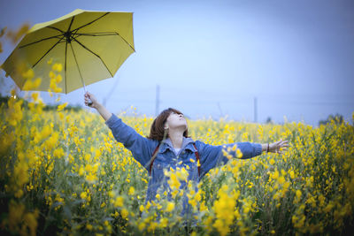 Young woman with yellow flowers in field