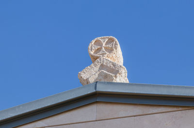 Low angle view of statue against building against clear blue sky