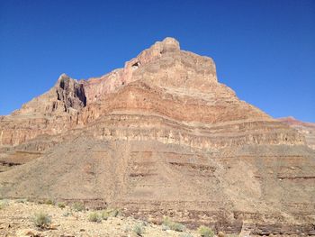 Low angle view of rock formations against clear blue sky