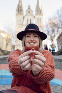 Portrait of smiling young woman holding ring 