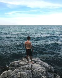 Rear view of man looking at sea against sky