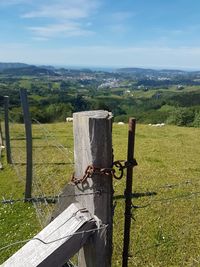 Close-up of wooden posts on field against sky