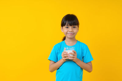 Portrait of smiling boy standing against yellow background