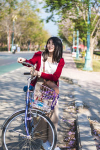 Woman with bicycle standing on road