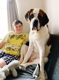 Portrait of young boy with  saint bernard dog sitting at home