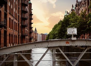 Bridge over canal amidst buildings against sky during sunset