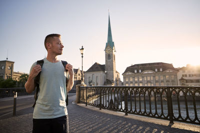 Man standing by railing in city against clear sky