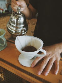 Close-up of hand holding tea cup on table