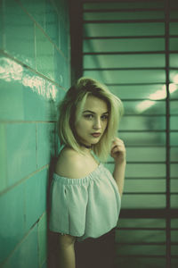 Portrait of young woman standing by window