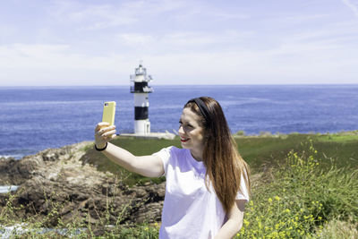 Woman photographing sea against sky