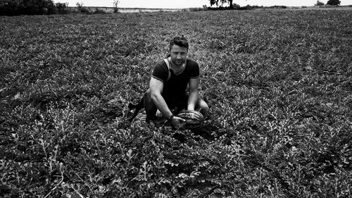 Portrait of man holding watermelon on field