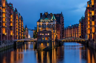 Bridge over river in city at dusk