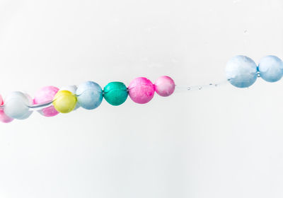 Close-up of multi colored balloons against white background