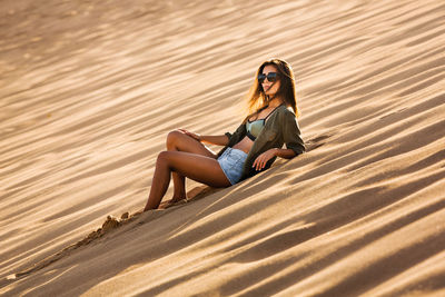 Full length portrait of woman sitting on sand