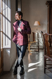 Young man looking away while standing against building