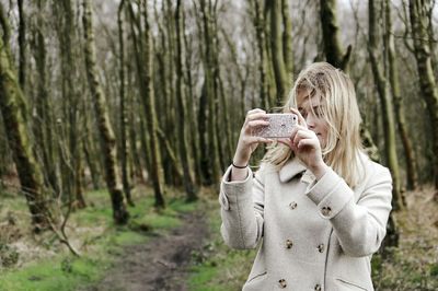 Woman taking photo with phone in forest