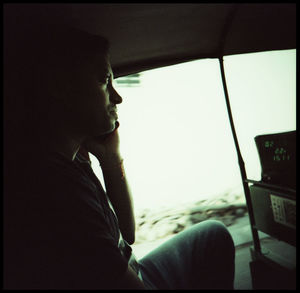 Side view portrait of young man sitting in car