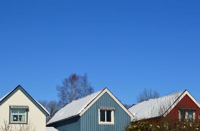 Houses against clear blue sky during winter