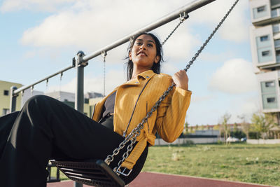 Young woman enjoying on swing at playground