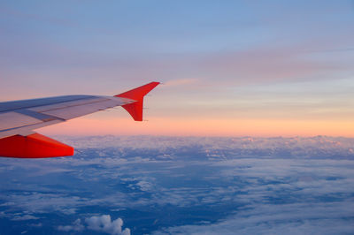 Close-up of airplane wing against sky during sunset