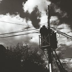 Low angle view of power lines against cloudy sky