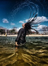 Rear view of woman flipping hair in sea