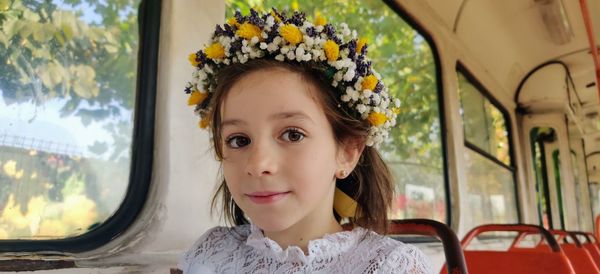 Portrait of girl wearing flowers while sitting in bus