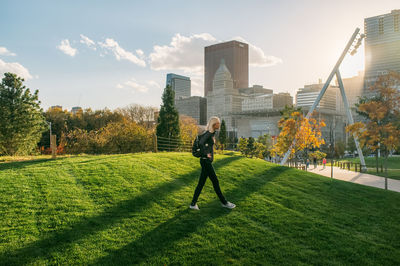 Woman walking in millennium park against modern buildings in city