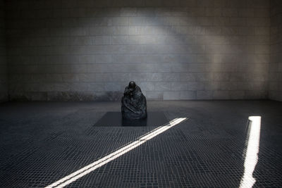 Rear view of person sitting on road against wall