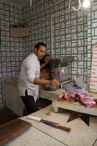 Butcher weighing meat on scale at store