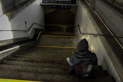 Rear view of man sitting on staircase