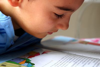 Close-up of boy reading book in classroom