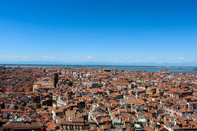 Aerial view of cityscape by sea against clear blue sky