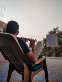 Rear view of man sitting on chair