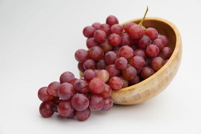 High angle view of grapes in bowl against white background